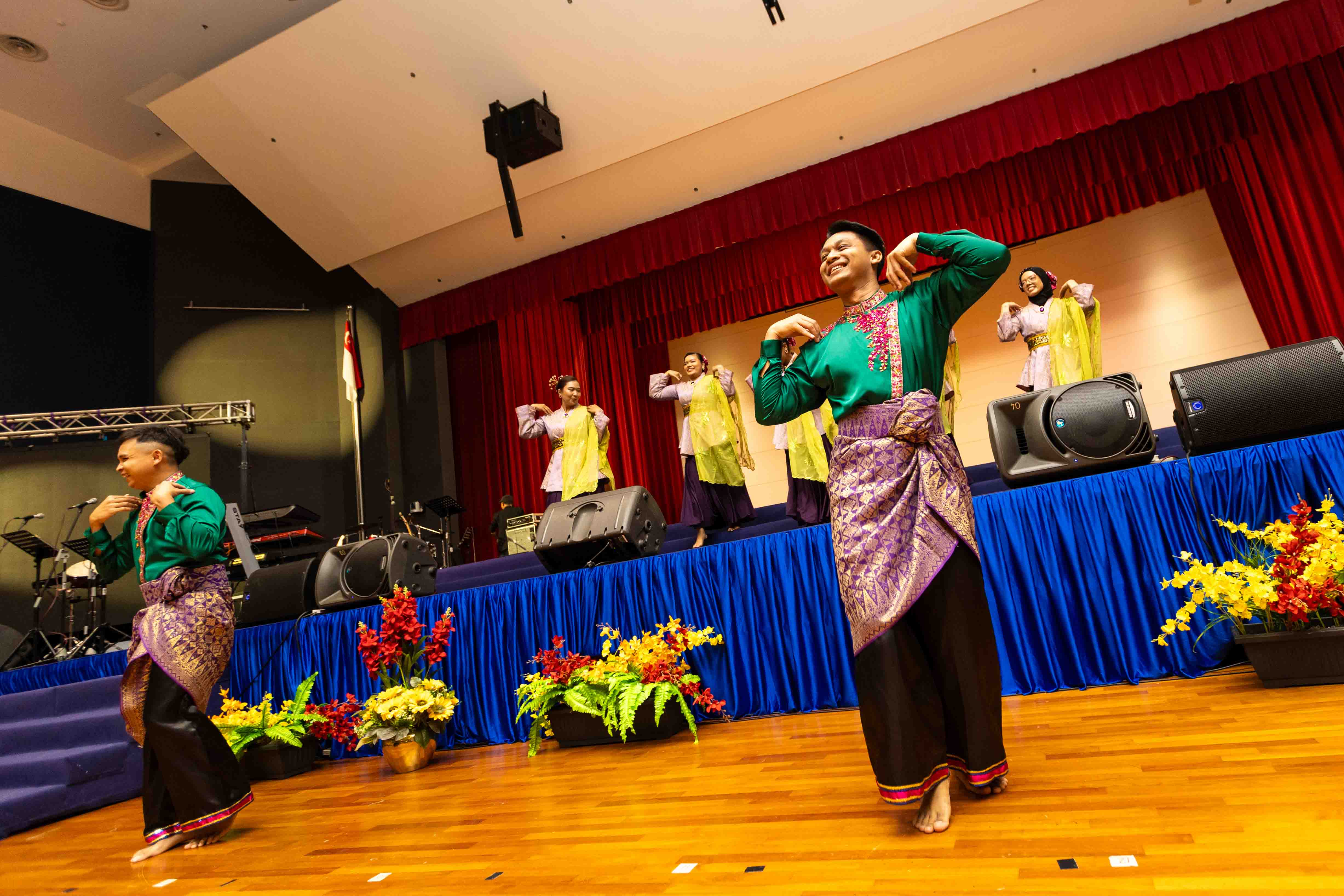 Performers in traditional attire present a cultural dance performance on stage.